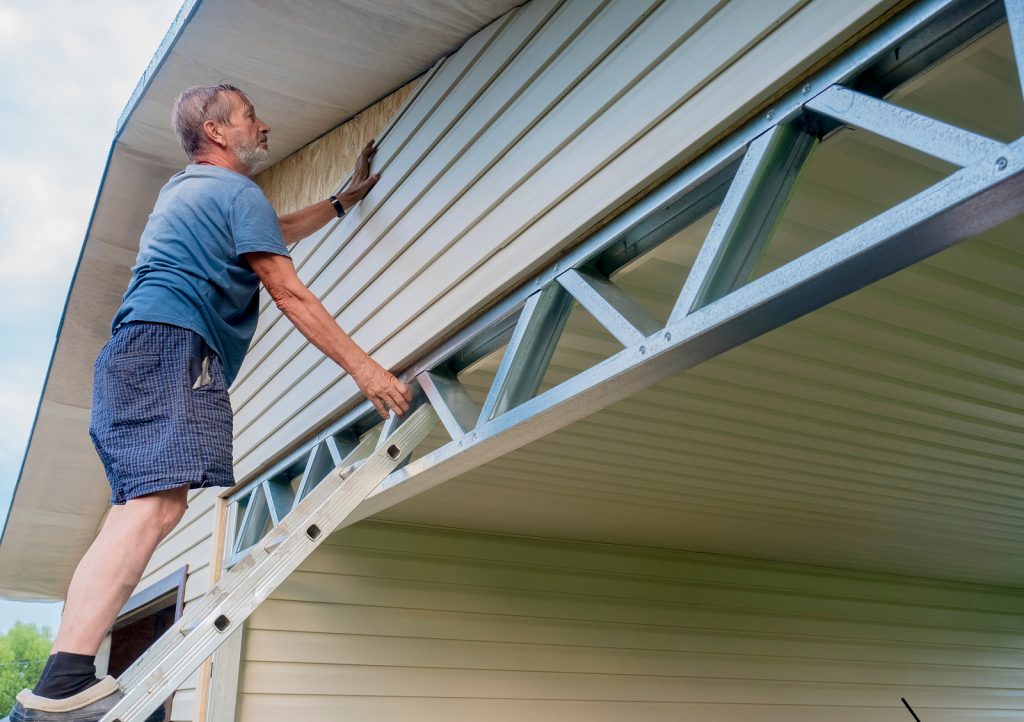 A Hackensack siding contractor installs plastic siding on the facade of the house.